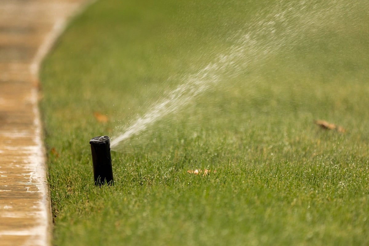 irrigation sprinkler watering lawn for healthy soil